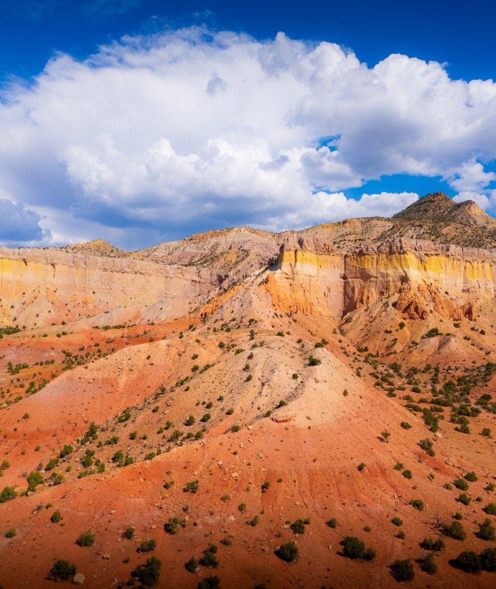 Colorful cliffs of Ghost Ranch, New Mexico – Stunning red and yellow striped rock formations under dramatic clouds in the iconic Ghost Ranch area.