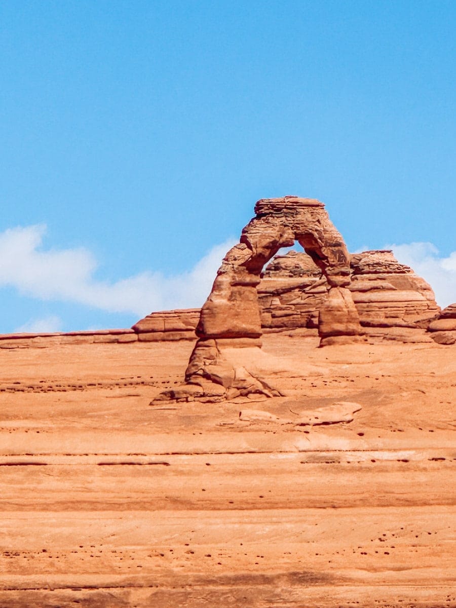 Close-up view of Delicate Arch, the iconic freestanding sandstone arch in Arches National Park, set against soft blue skies and red desert rock.