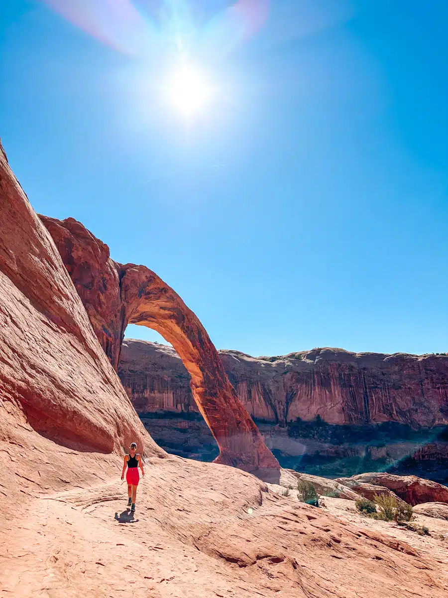 Impressive sandstone arch standing tall against a clear sky in the Utah desert landscape The author's wife is also in the picture