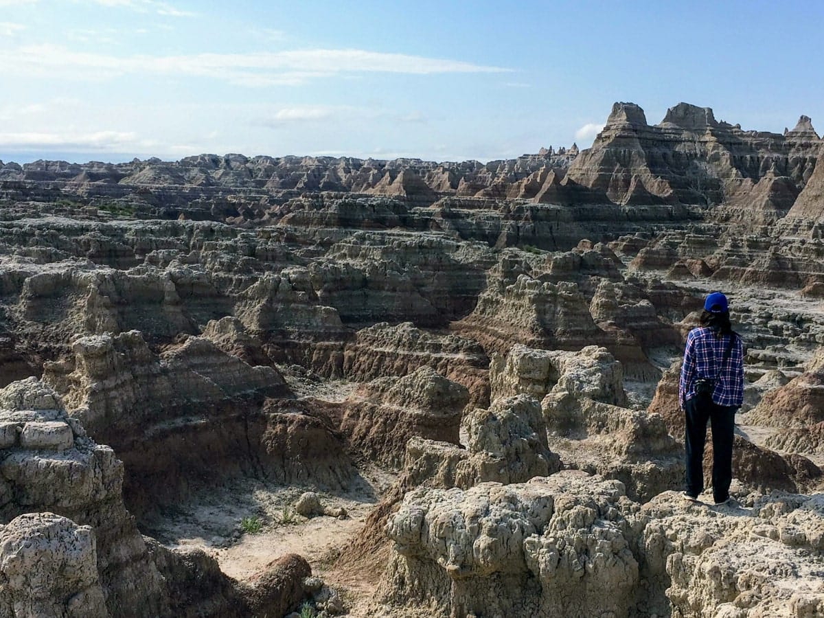 Woman gazing out over the dramatic layered canyons of the White River Valley Overlook in Badlands National Park.
