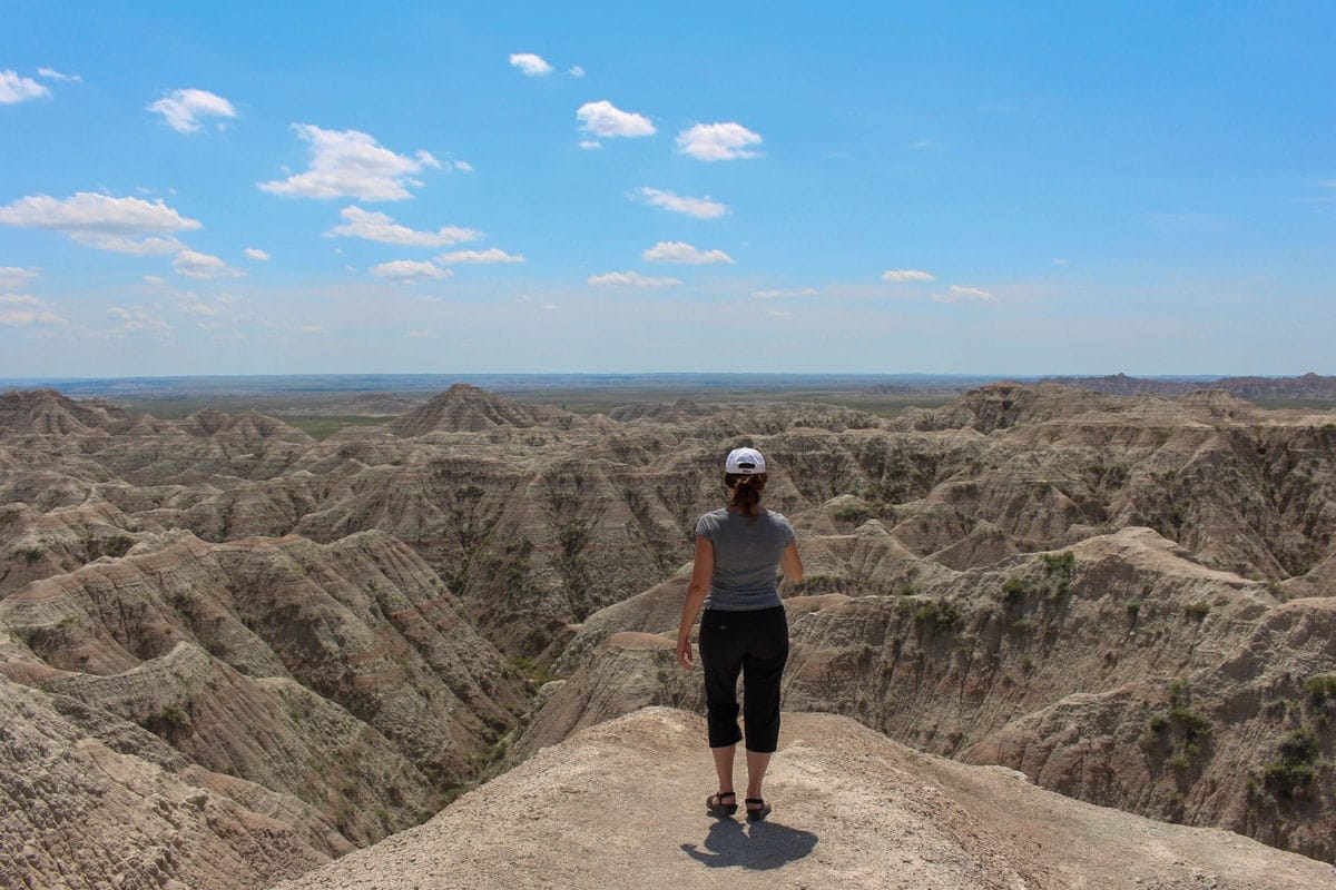 Woman gazing out over the dramatic layered canyons of the White River Valley Overlook in Badlands National Park.