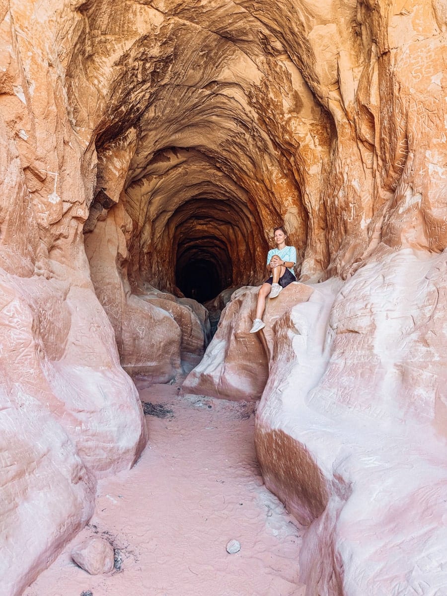 the author's wife posing on a stone inside a deep tunnel in kanab