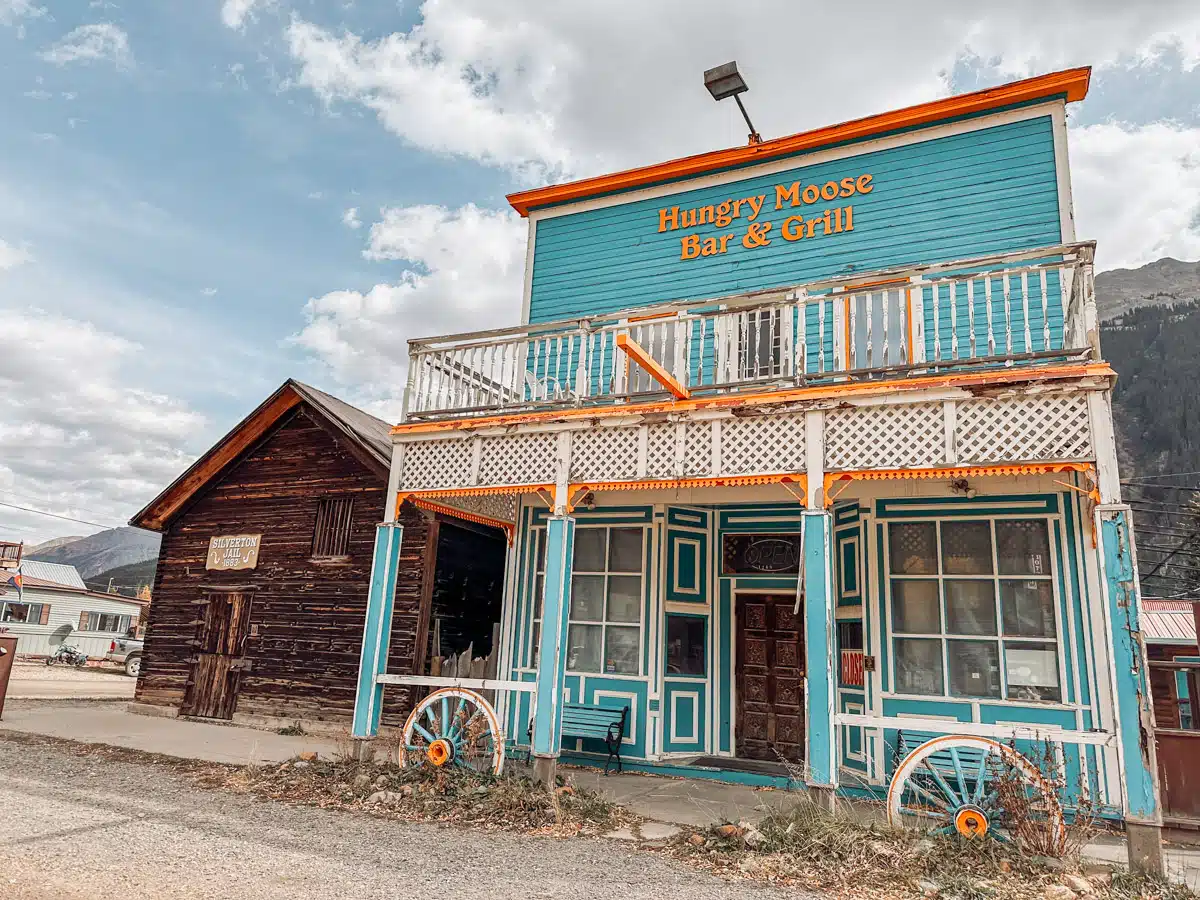 The colorful facade of the Hungry Moose Bar & Grill in Silverton, Colorado, next to the historic Silverton Jail from 1883.