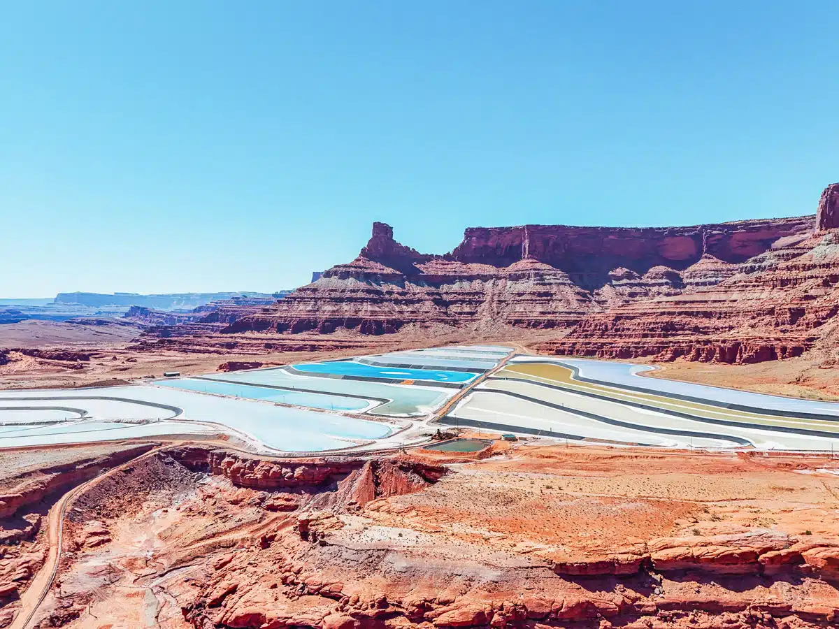 Bright blue and yellow salt ponds framed by red mesas in Moab’s Potash mining area