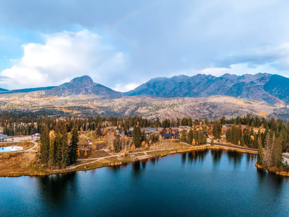 A peaceful mountain lake at sunset with golden aspens and pine trees, set against the backdrop of the San Juan Mountains near Durango.