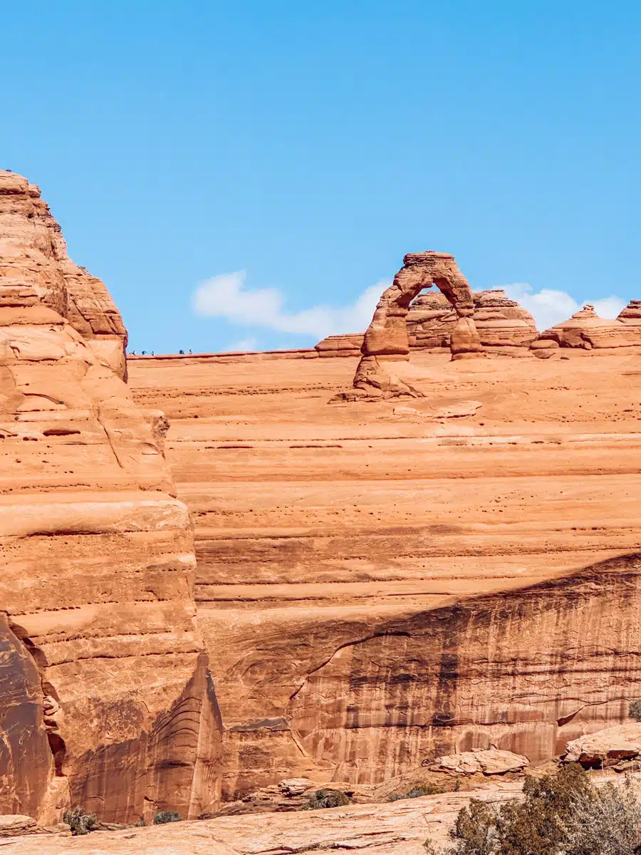 Delicate Arch rising above red sandstone in Arches National Park on a clear fall day
