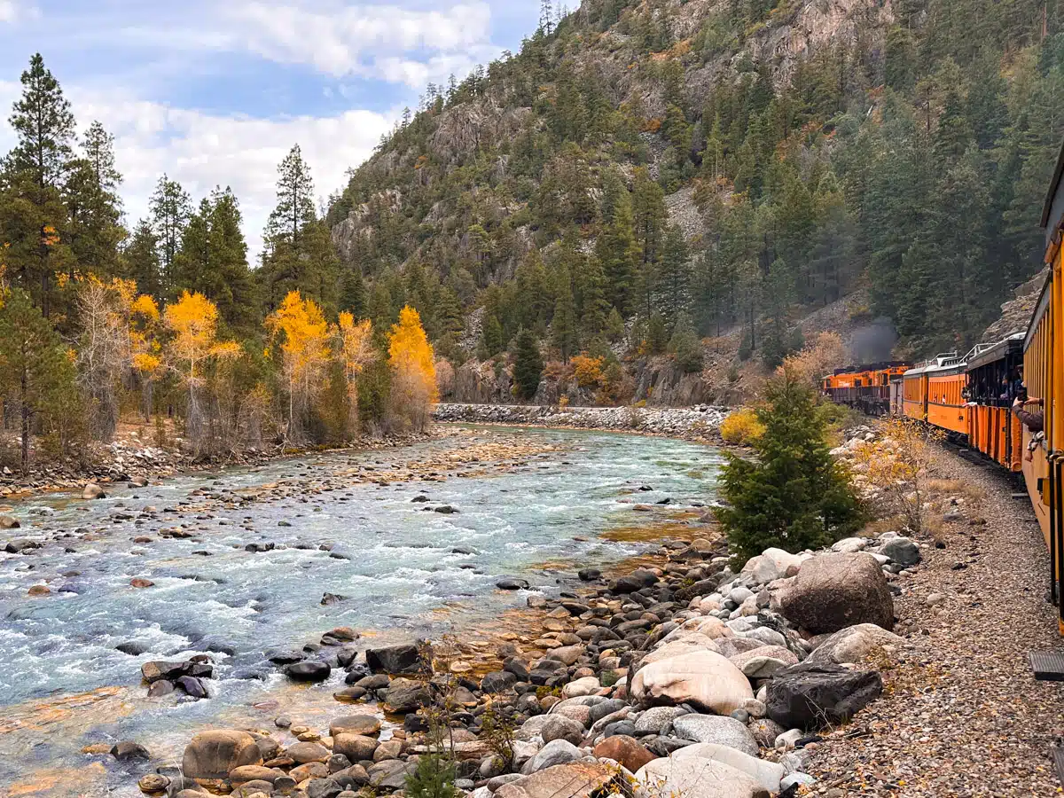 stunning view of the animas river and golden aspens with the front of the steam train